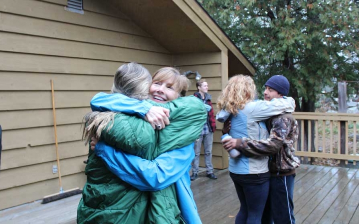 A group of people embrace during the family seminar of an outward bound intercept course.